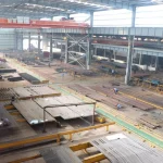 Inside view of DHB Boiler manufacturing workshop equipped with advanced membrane wall production lines and heavy-duty cranes.